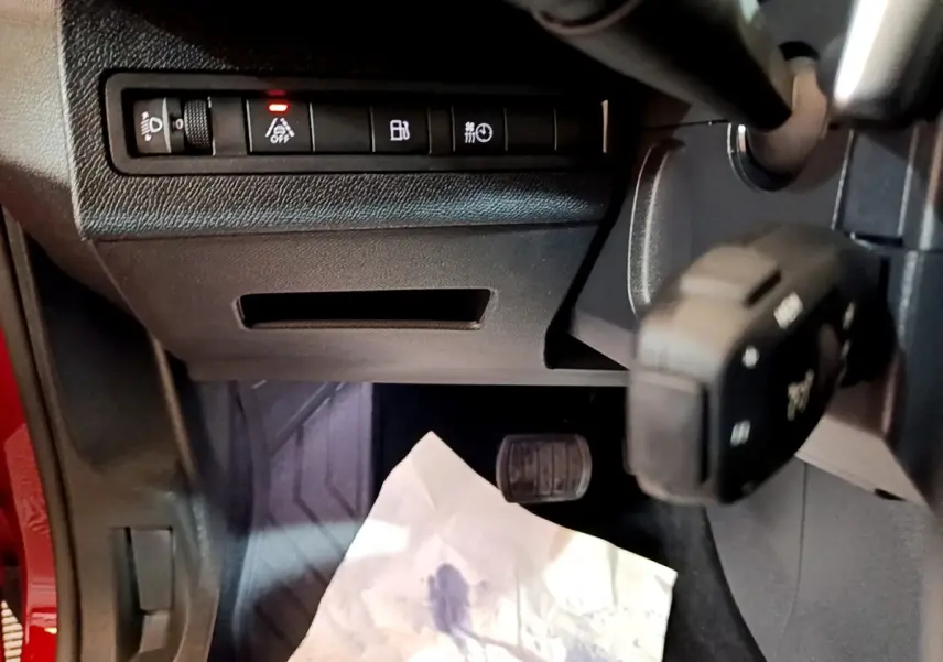 Détail intérieur côté gauche du Peugeot 3008 hybride 2021, montrant commandes et pédale avec partie de la carrosserie rouge.