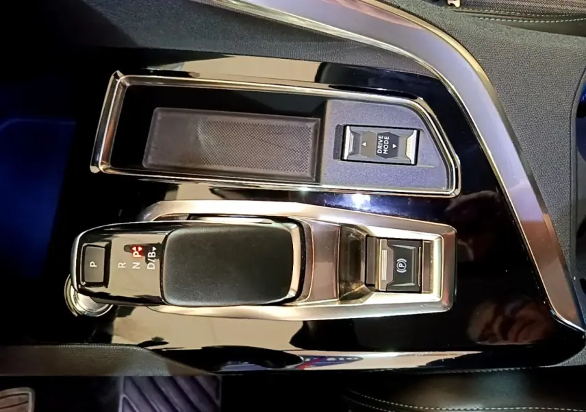 Vue rapprochée de la console centrale noire brillante du Peugeot 3008 hybride, avec levier de vitesses automatique et bouton Drive Mode.