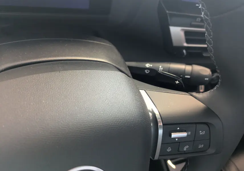 Gros plan sur la partie droite du volant noir de la Citroën C4 2025, avec commandes intégrées et palettes au volant.