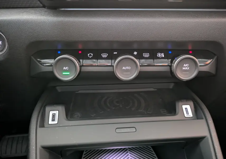 Gros plan sur la console centrale noire du Citroën C4 2025, montrant les commandes de climatisation et deux ports USB.