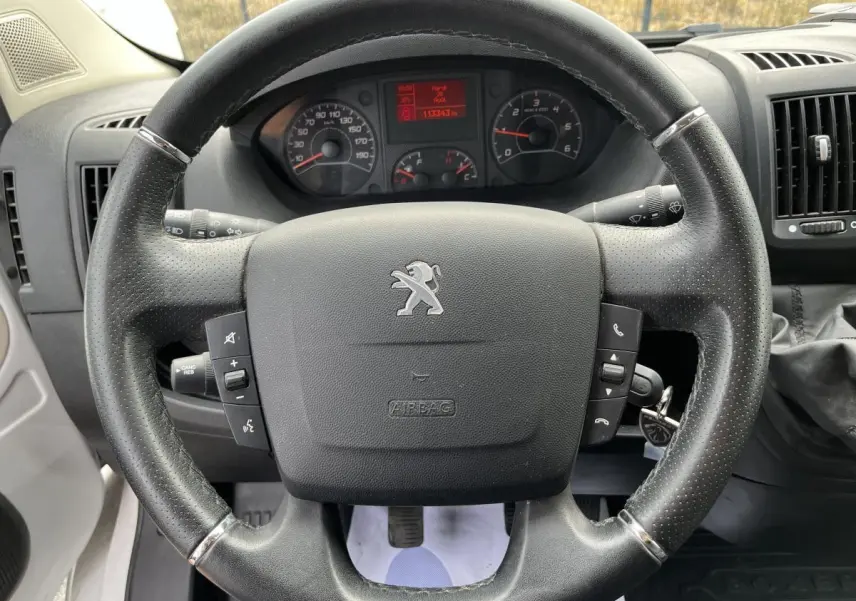 Vue rapprochée du volant en cuir noir du Peugeot Boxer Fourgon 2023 avec tableau de bord et compteur digital rouge.