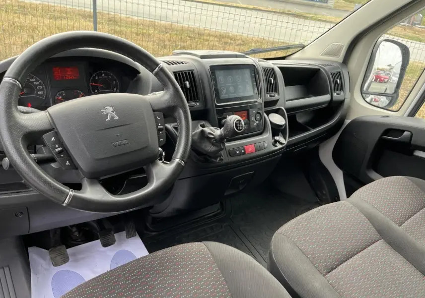 Vue intérieure côté conducteur du Peugeot Boxer Fourgon 2023, tableau de bord noir avec volant cuir et console centrale tactile.