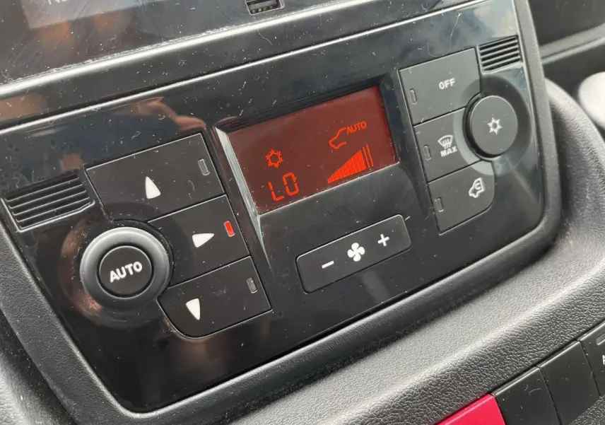 Détail du panneau de commande de la climatisation automatique du Peugeot Boxer Fourgon blanc, affichage rouge et boutons noirs.