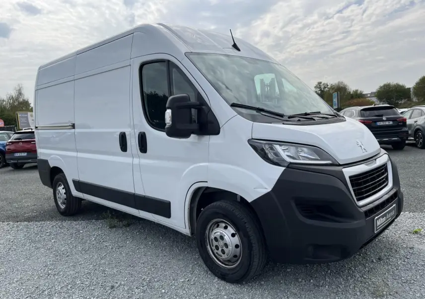 Peugeot Boxer Fourgon blanc en 3/4 avant droit, avec porte latérale coulissante et pare-chocs noirs robustes.