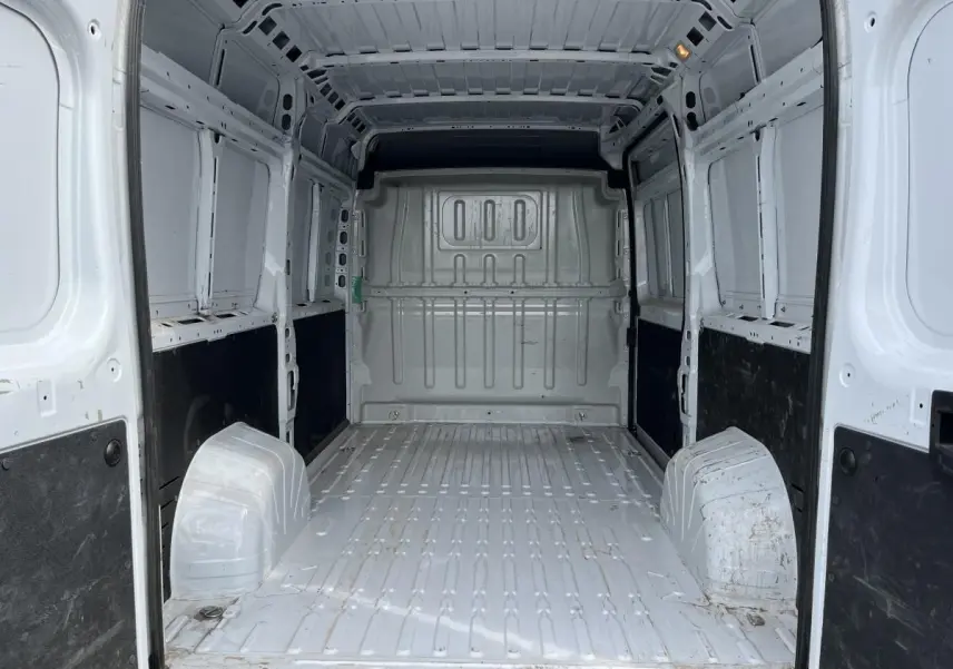 Vue intérieure arrière du fourgon Peugeot Boxer blanc, montrant l'espace de chargement tôlé et les protections latérales noires.