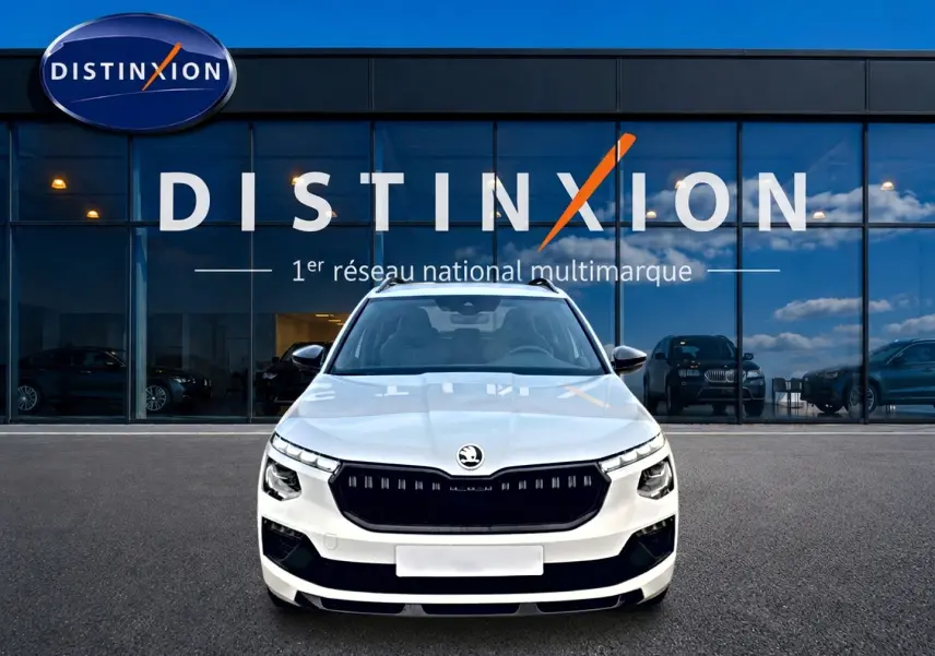 Vue avant frontale du Skoda Kamiq blanc nacré avec calandre noire et toit panoramique, devant une vitrine Distinxion.