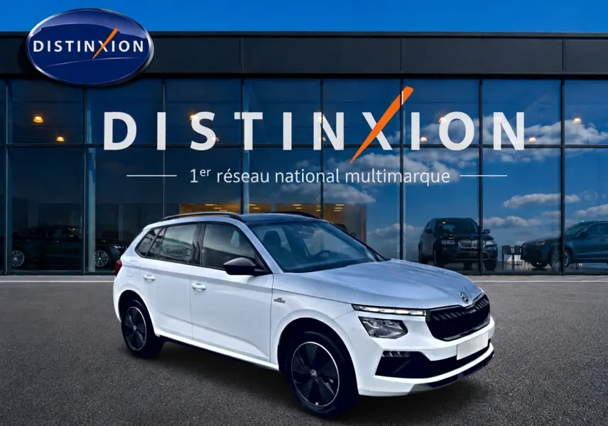 Vue 3/4 avant droite d'un Skoda Kamiq blanc nacré avec toit noir et jantes alliage noires devant un showroom Distinxion.