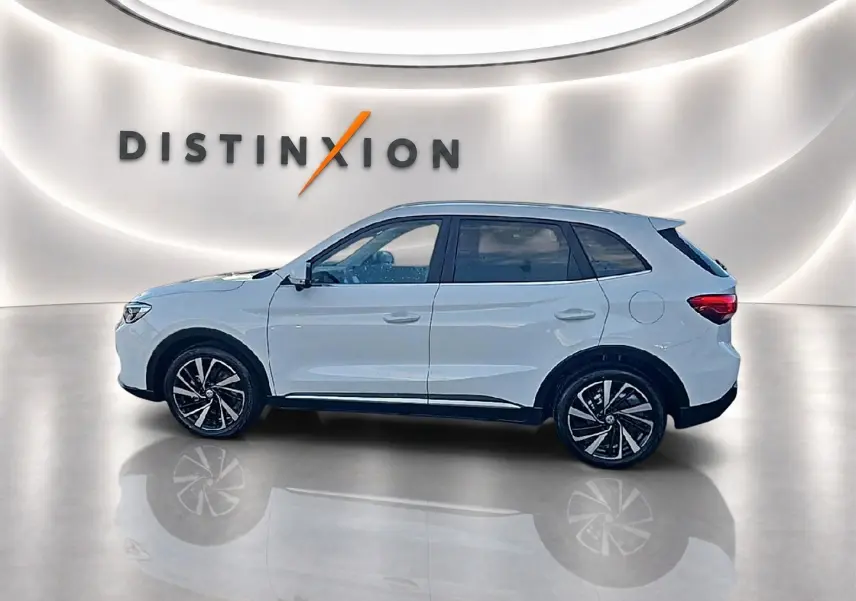 Vue de profil côté gauche du MG Motor ZS blanc 2026 dans un showroom avec logo Distinxion en arrière-plan.