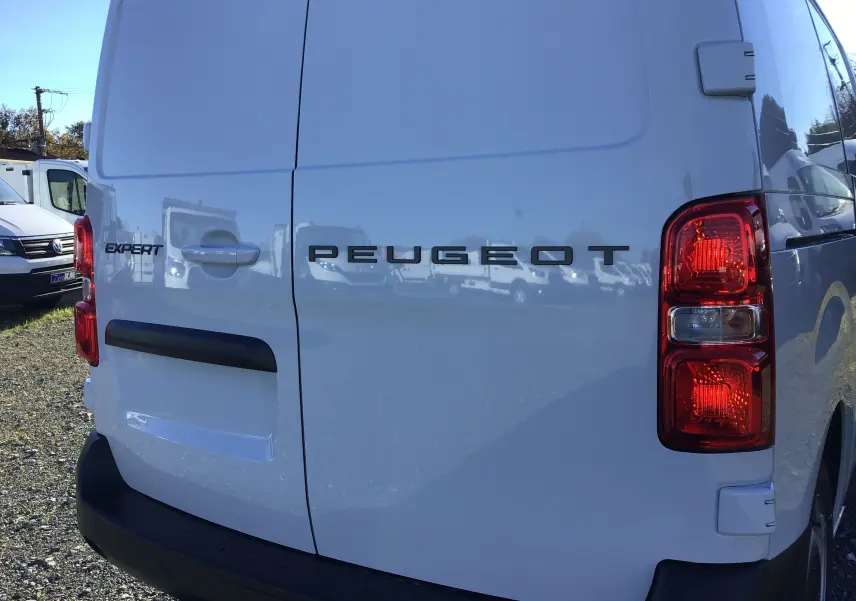 Vue arrière droite d'un fourgon Peugeot Expert blanc avec feux arrière rouges et logo visible sur les portes.