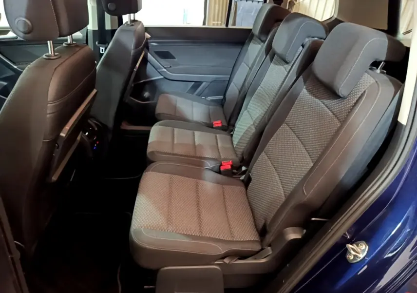 Vue latérale des sièges arrière gris foncé du Volkswagen Touran bleu 2021, montrant trois places individuelles.
