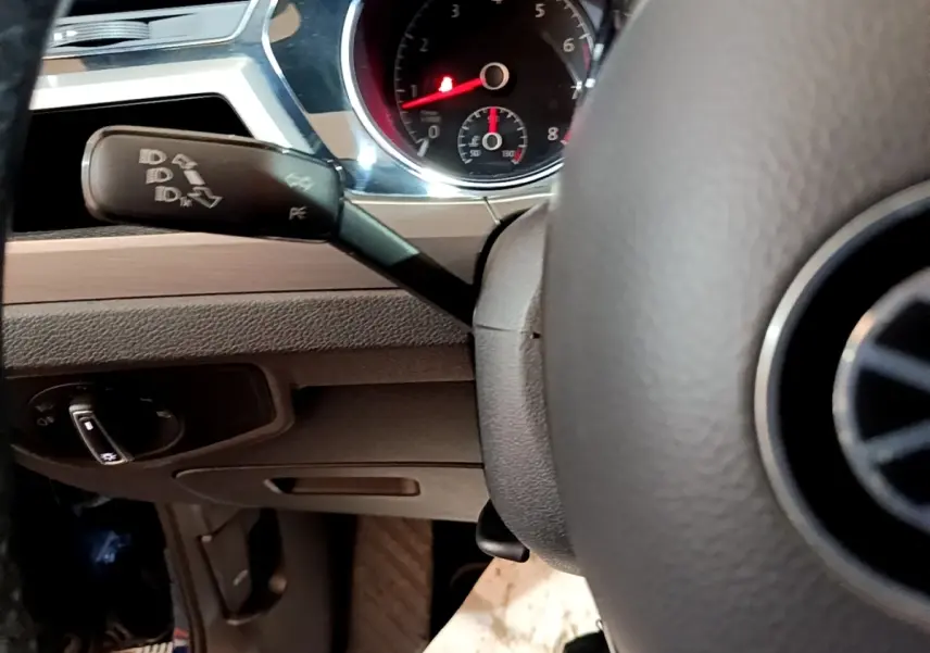 Gros plan sur le volant et le commodo gauche du tableau de bord d'un Volkswagen Touran bleu 2021.