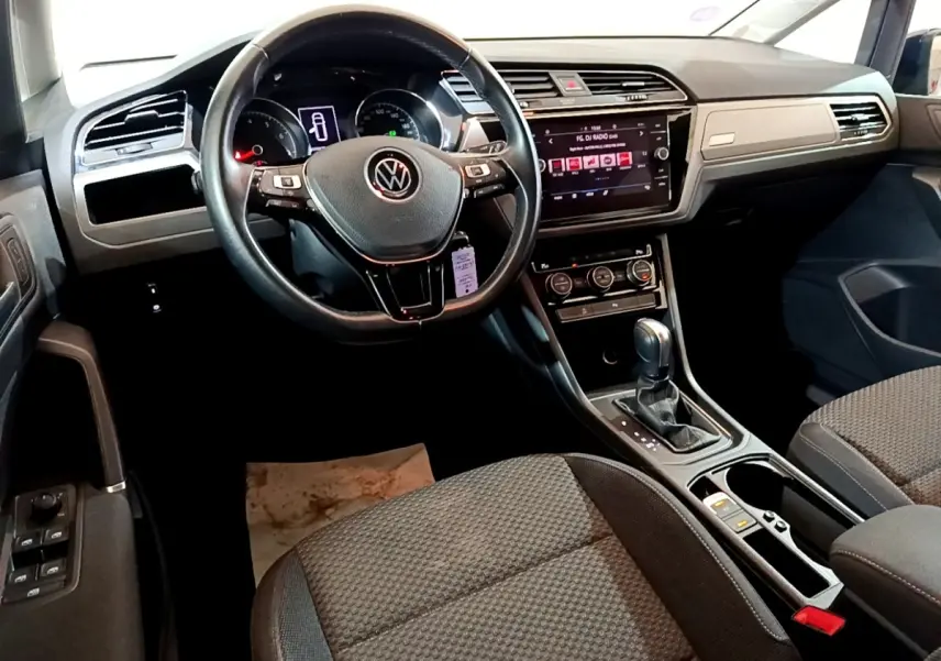Intérieur Volkswagen Touran 1.5 TSI EVO DSG7 United 2021 vu côté conducteur, volant cuir et écran tactile central.