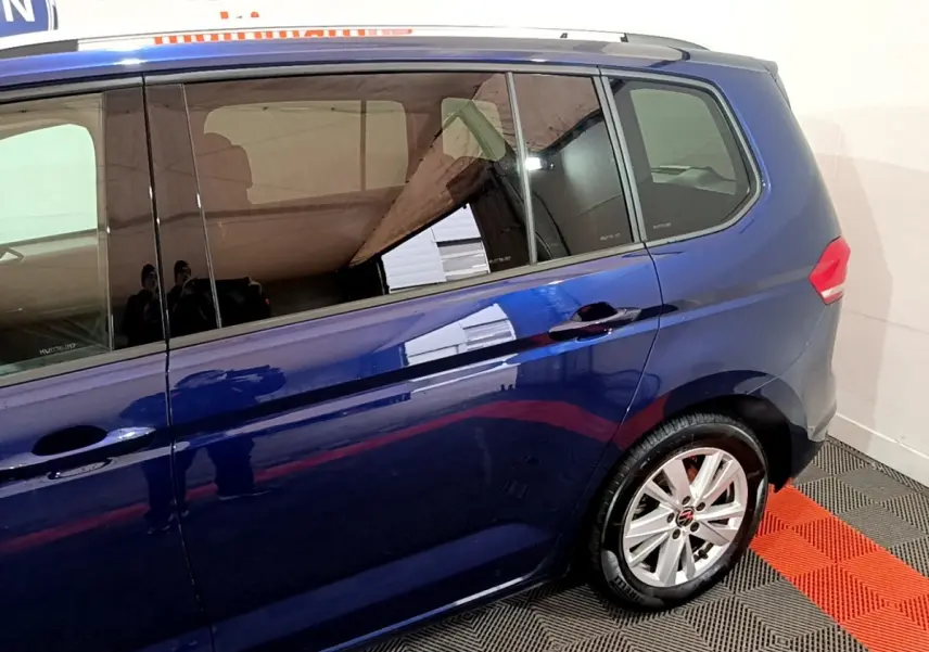 Vue latérale côté droit du Volkswagen Touran bleu 2021 avec jantes alliage et vitres teintées.