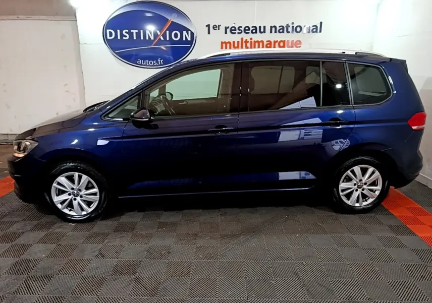 Profil latéral gauche d'un Volkswagen Touran bleu 2021 garé en intérieur avec jantes alliage et vitres teintées.