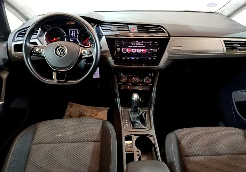 Intérieur Volkswagen Touran 2021, vue frontale du tableau de bord avec écran tactile et volant multifonctions noir.