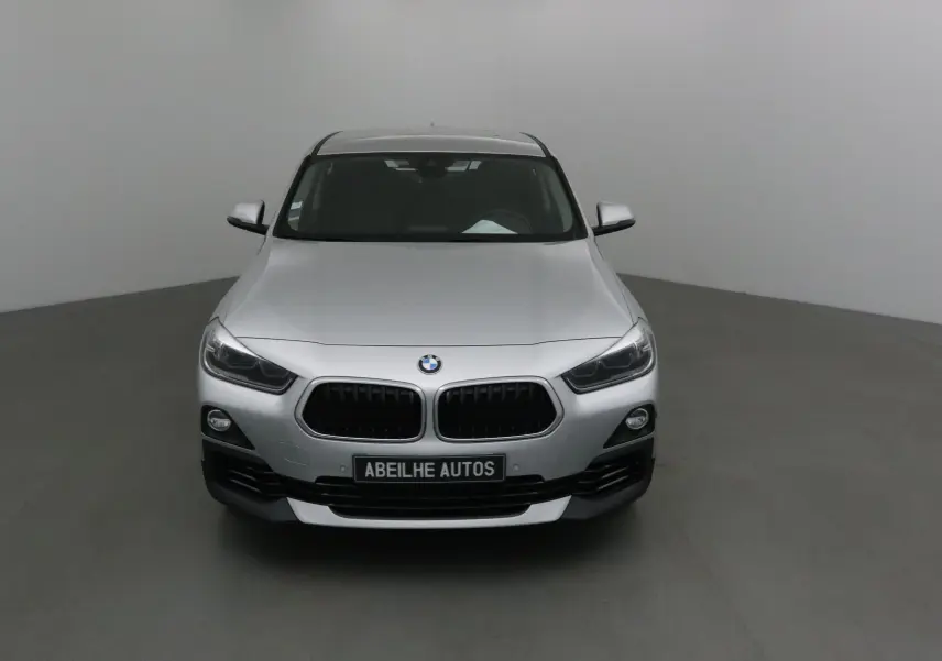 Vue frontale d'une BMW X2 gris clair métal 2018 avec calandre noire et plaque Abeilhe Autos visible.