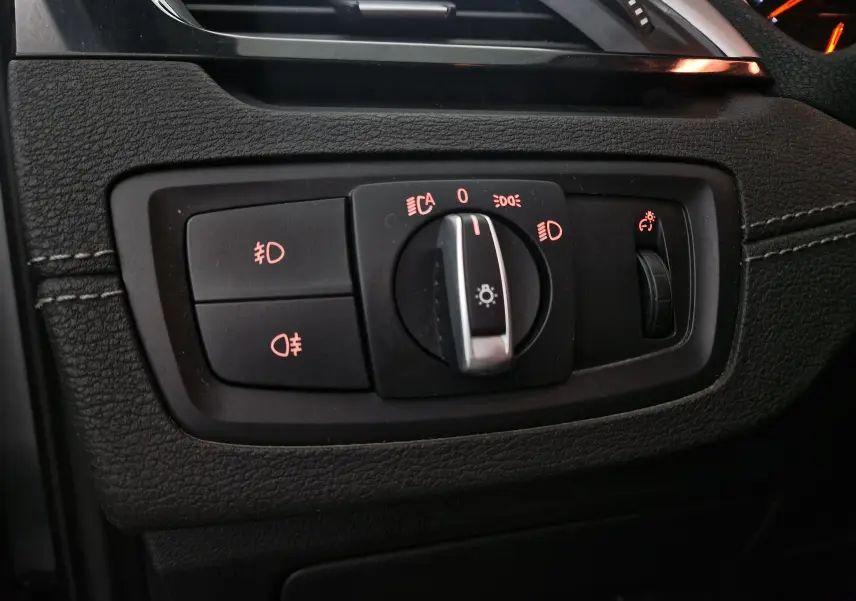 Gros plan sur le bouton de commande des phares et éclairage intérieur du BMW X2 gris clair métal, finition Lounge.