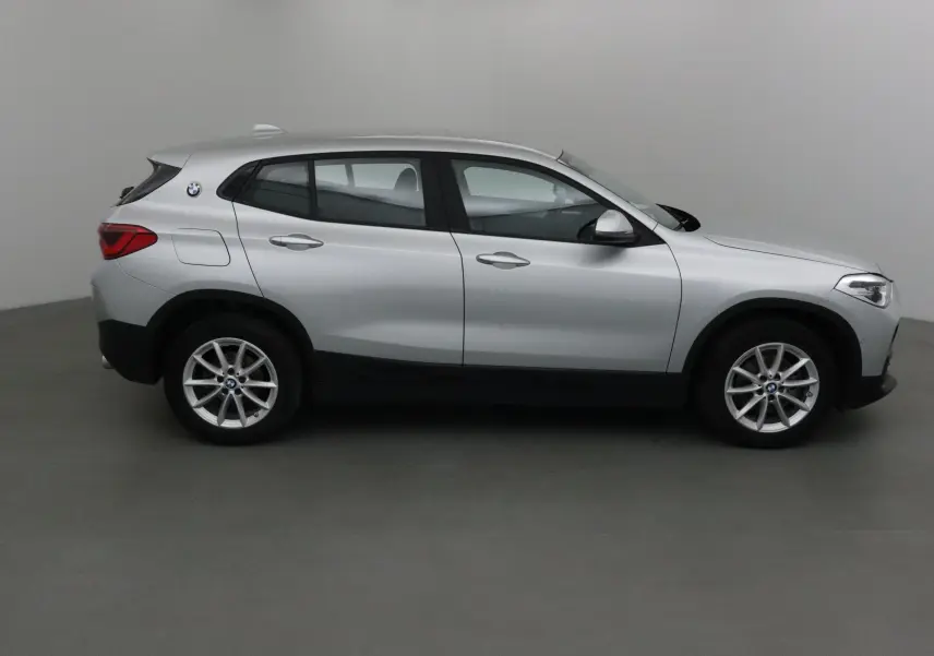 Vue de profil côté gauche d’un BMW X2 gris clair métal de 2018 avec jantes alliage et logo BMW visible à l’arrière.
