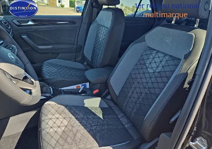 Vue intérieure côté gauche montrant les sièges avant en tissu noir et gris avec logo R du Volkswagen T-Roc 2025 noir perle.