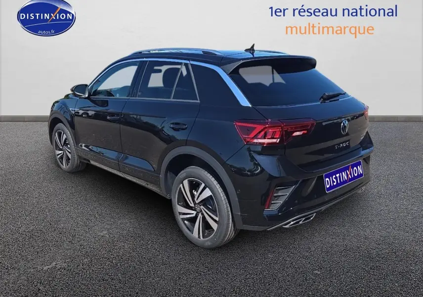 Volkswagen T-Roc noir perle en vue 3/4 arrière droit, avec jantes alliage et barres de toit argentées.