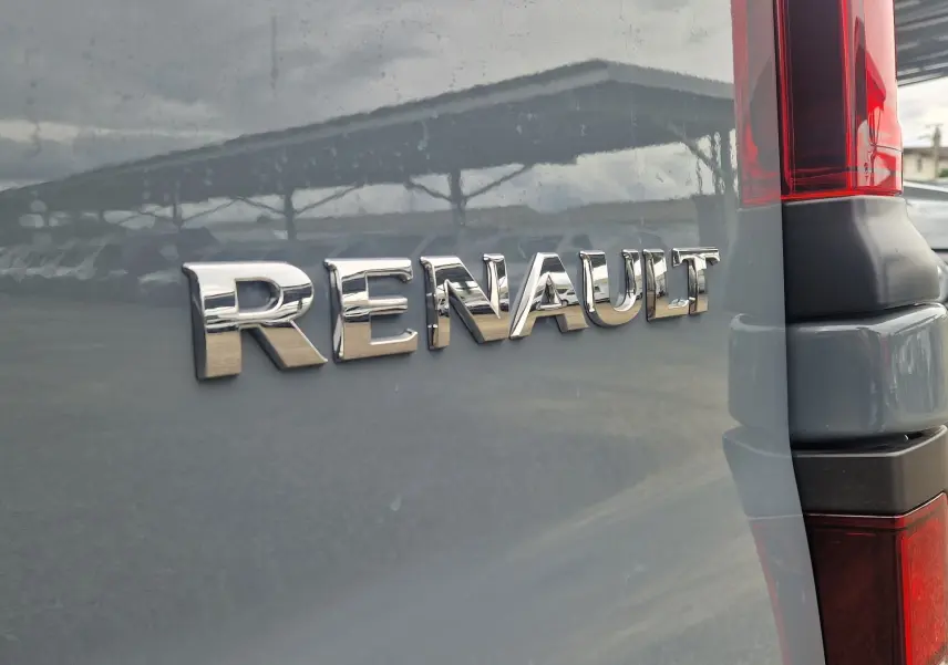 Gros plan sur l'arrière gris Highland du Renault Trafic Fourgon avec logo chromé et feu arrière rouge visible.