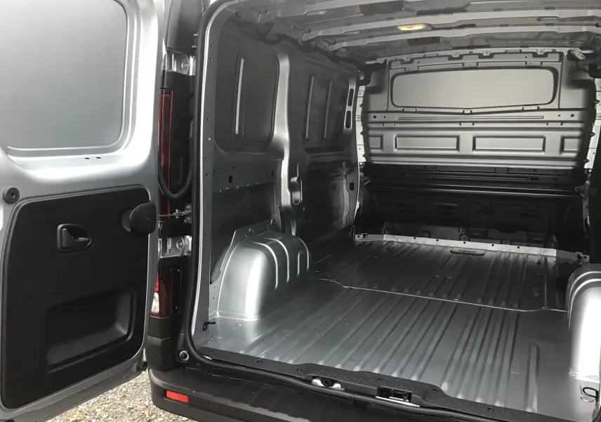 Vue arrière ouverte du Renault Trafic Fourgon gris Highland montrant l'espace de chargement vide et la cloison intérieure.
