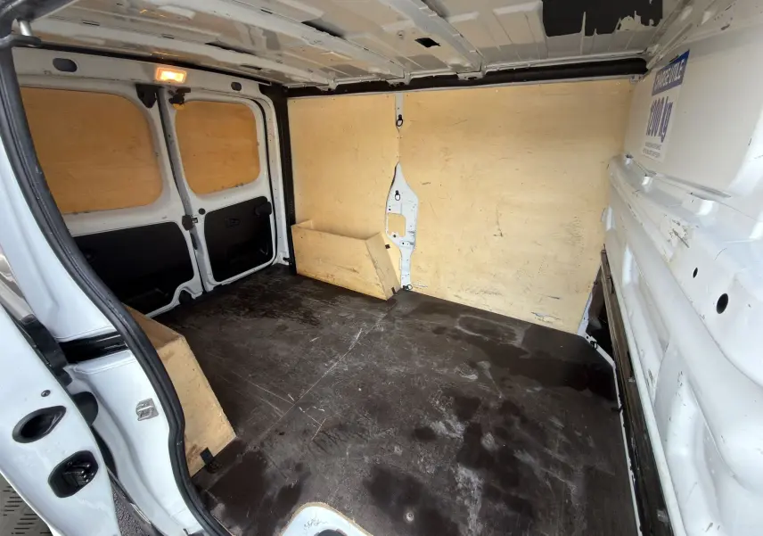Vue intérieure arrière du fourgon blanc Renault Trafic L1H1 2024, montrant l'espace de chargement avec parois en bois.