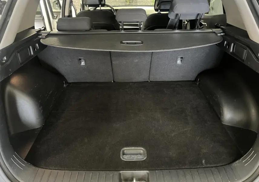 Coffre ouvert du Kia Sportage blanc, vue arrière montrant la plage arrière et les sièges noirs.