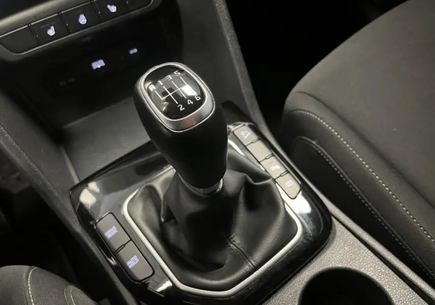 Le levier de vitesses manuel noir du KIA Sportage 2022 vu en gros plan depuis l'intérieur côté conducteur.