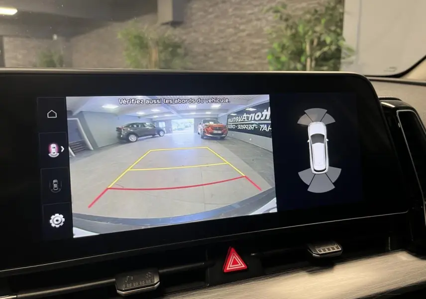 Écran tactile intérieur montrant la caméra de recul et l’aide au stationnement du Kia Sportage blanc, vue arrière.
