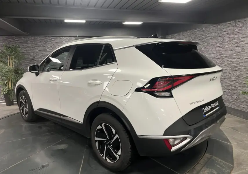 Vue 3/4 arrière droit du KIA Sportage blanc nacré avec jantes alliage 18 pouces et feux arrière LED.