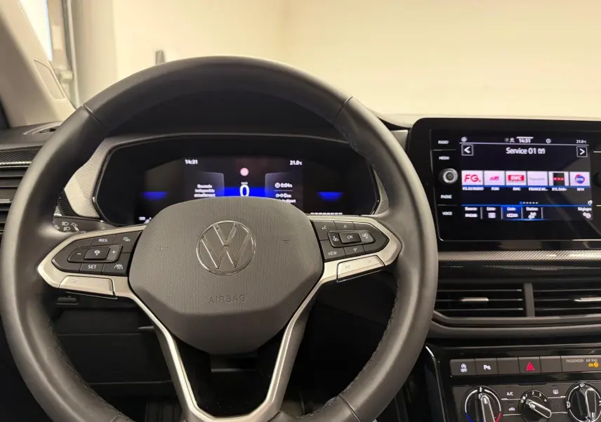 Vue intérieure centrée sur le volant et le tableau de bord numérique du Volkswagen T-Cross gris cendre 2025.