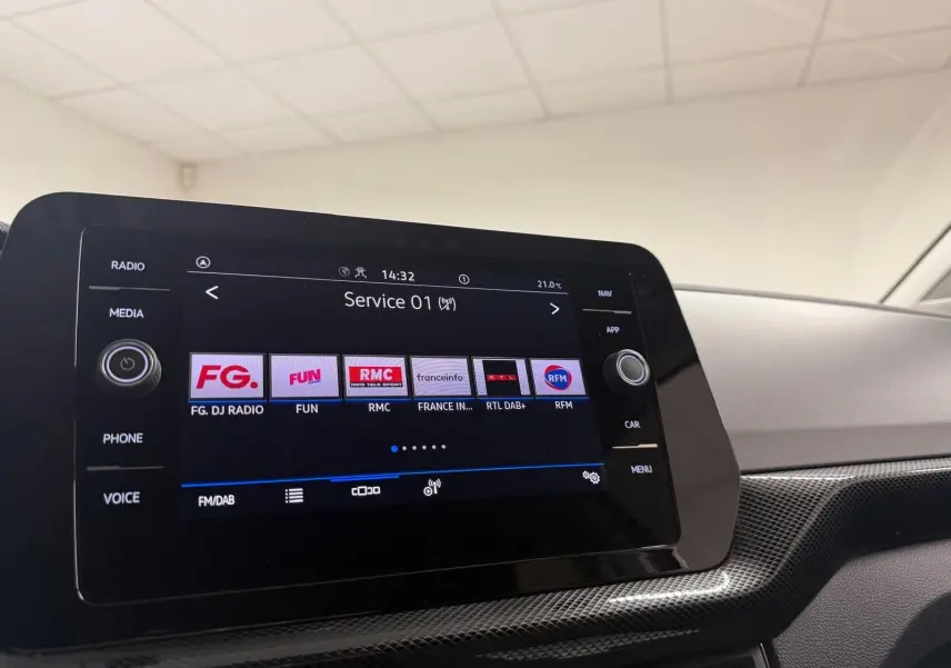 Vue intérieure du tableau de bord du Volkswagen T-Cross gris cendre 2025, écran tactile multimédia affichant les stations radio.