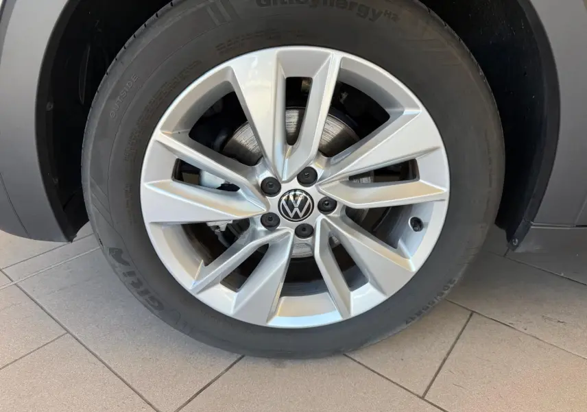 Gros plan sur la roue avant droite du Volkswagen T-Cross gris cendre 2025 avec jante alliage à dix branches.