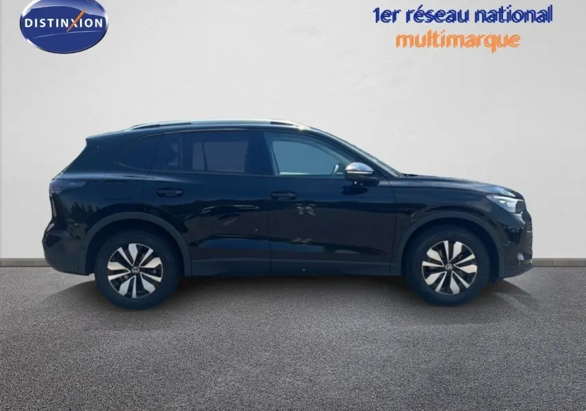 Vue de profil côté gauche d'un Volkswagen Tiguan noir Grenadilla métallisé, avec jantes bicolores et lignes épurées.