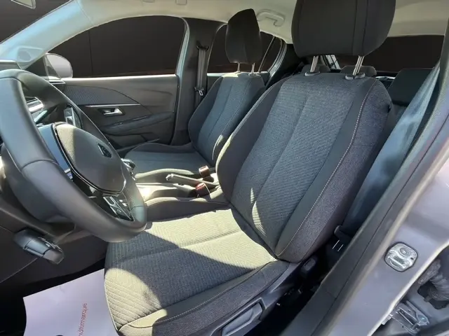 Vue intérieure côté conducteur de la Peugeot 208 100 ch Style 2025 gris clair, sièges tissu et volant cuir multifonctions.