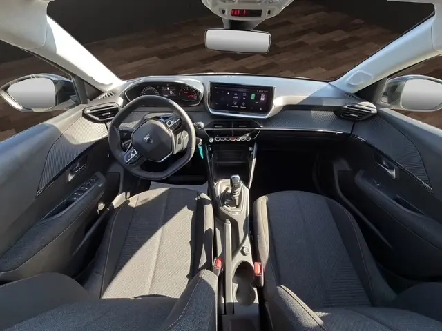 Vue intérieure avant de la Peugeot 208 100 ch Style 2025, volant cuir multifonctions, écran tactile central et boîte manuelle.