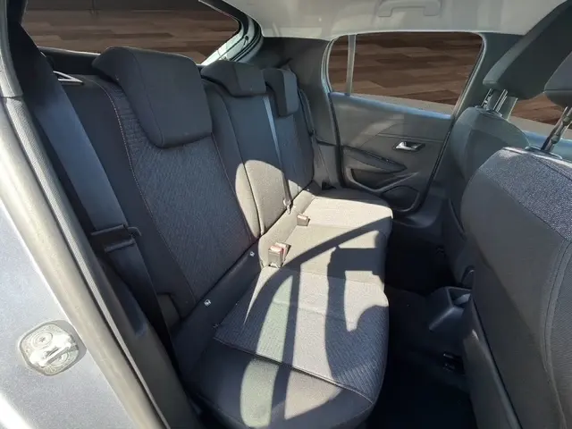 Vue intérieure arrière côté gauche de la banquette arrière grise de la Peugeot 208 100 ch Style 2025 avec sièges tissu et ceintures visibles.