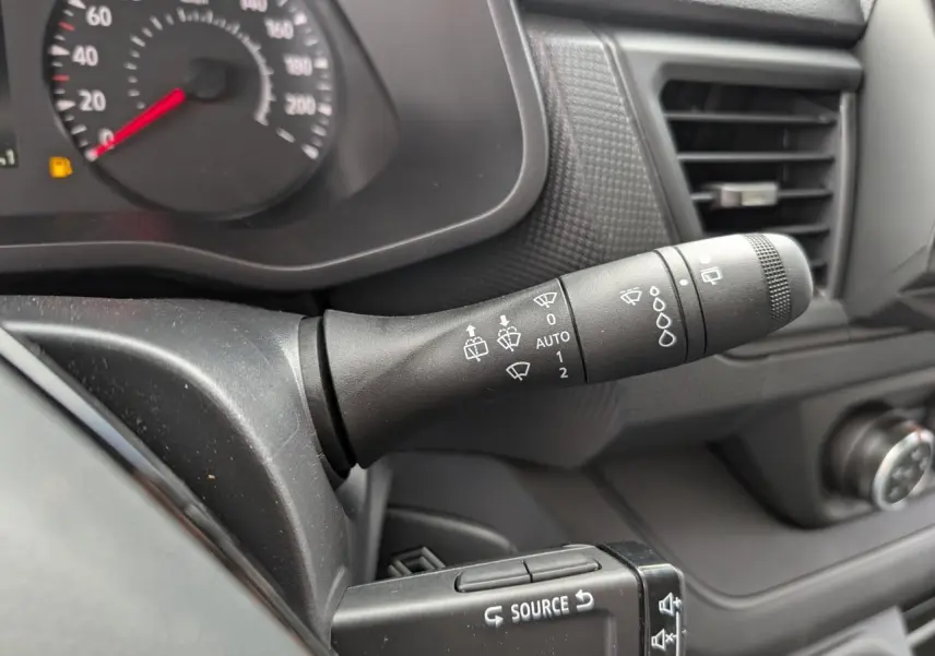 Gros plan sur la manette d’essuie-glace noire du tableau de bord du Renault Trafic Fourgon gris, avec compteur partiel.