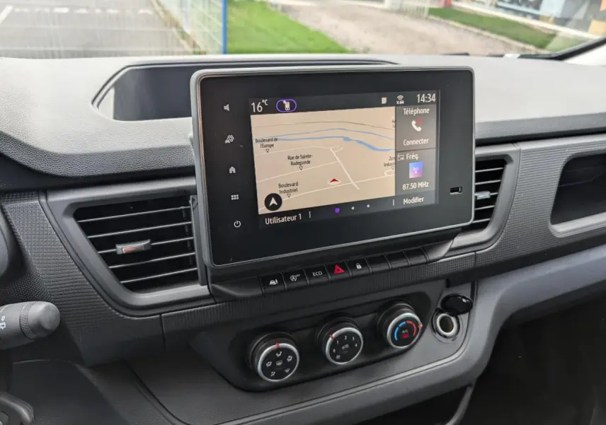 Vue rapprochée du tableau de bord du Renault Trafic Fourgon 2025, mettant en valeur l'écran tactile central et les commandes de climatisation.