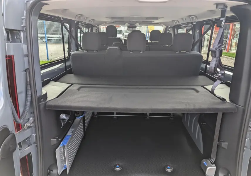 Vue arrière ouverte du Renault Trafic Fourgon gris 2025, montrant l'espace de chargement avec banquettes et ceintures de sécurité.