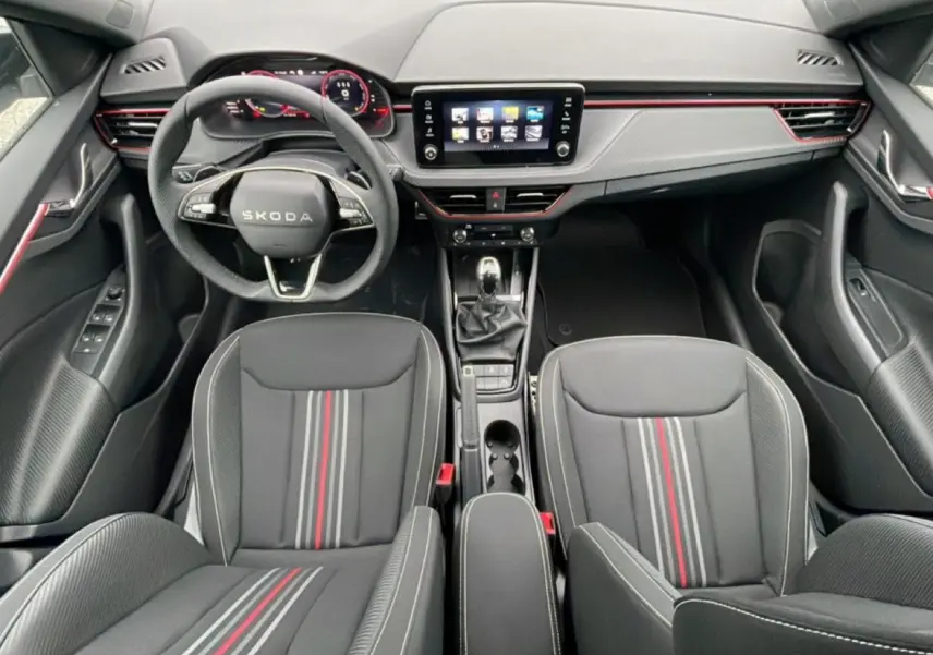 Vue intérieure frontale du Skoda Kamiq Monte Carlo 2026, sièges noirs avec bandes rouges et tableau de bord moderne.