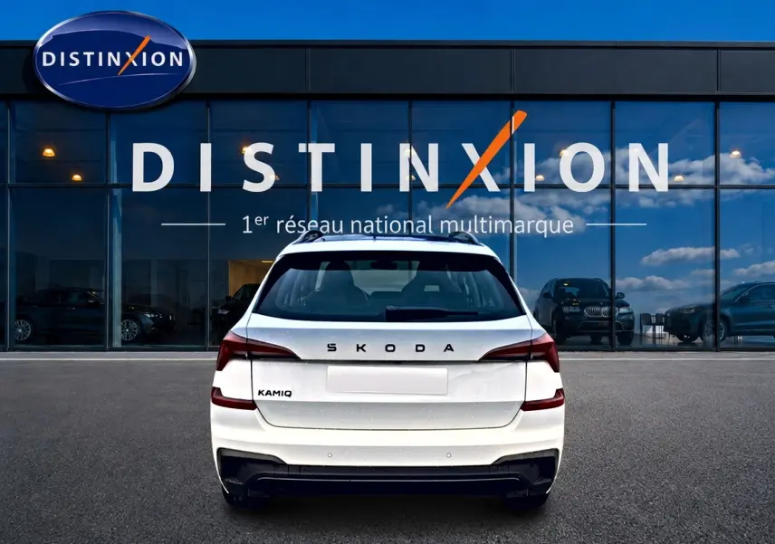 Vue arrière d'un Skoda Kamiq blanc nacré garé devant une vitrine avec logo Distinxion.