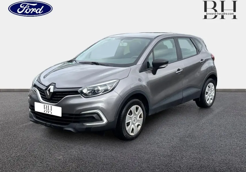 Renault Captur Gris Cassiopée en 3/4 avant droit, avec jantes acier et détails noirs sur les rétroviseurs.