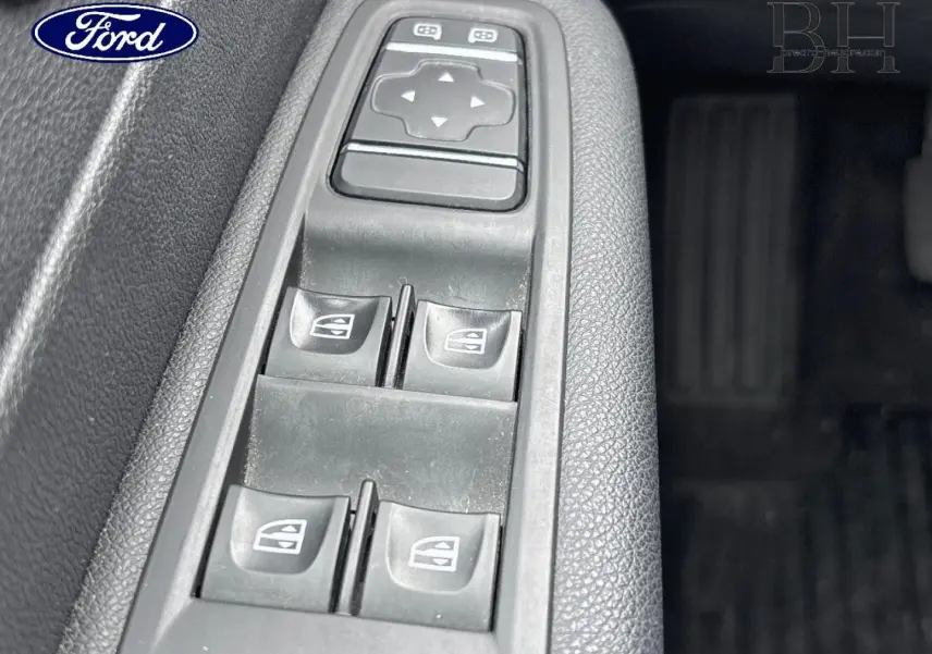 Panneau de commandes des vitres électriques côté conducteur d’un véhicule, avec boutons noirs sur plastique gris texturé.