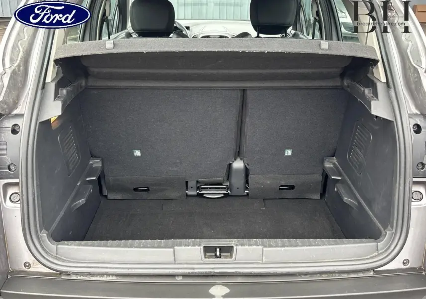 Coffre ouvert d’un Renault Captur gris Cassiopée, vue arrière montrant la banquette arrière et le plancher de coffre vide.
