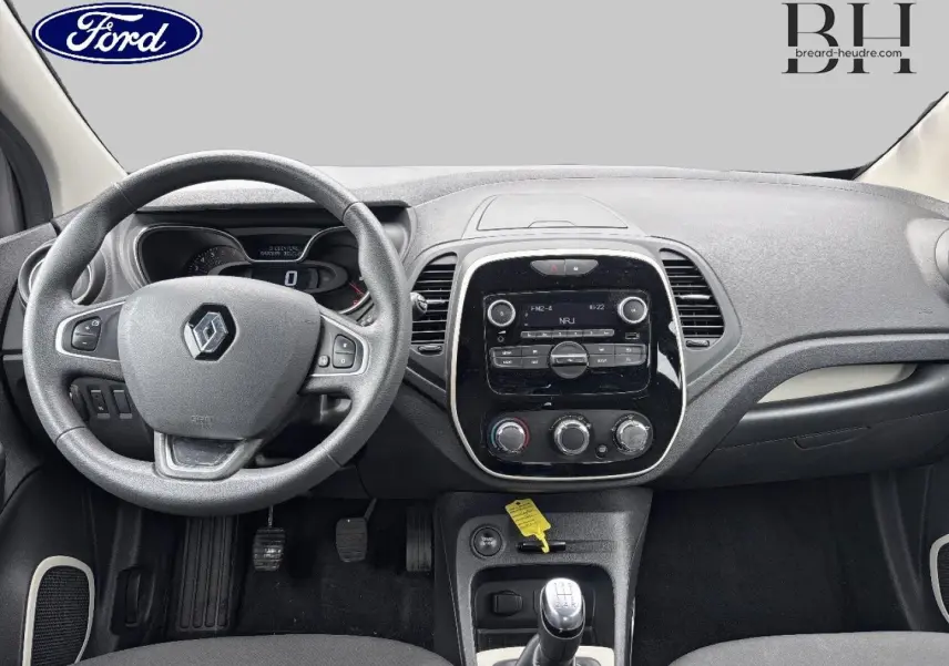 Vue intérieure avant du tableau de bord gris et volant Renault avec levier de vitesse manuel et écran central tactile.