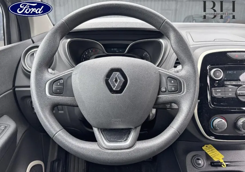 Vue intérieure centrée sur le volant Renault Captur gris avec tableau de bord et commandes visibles.