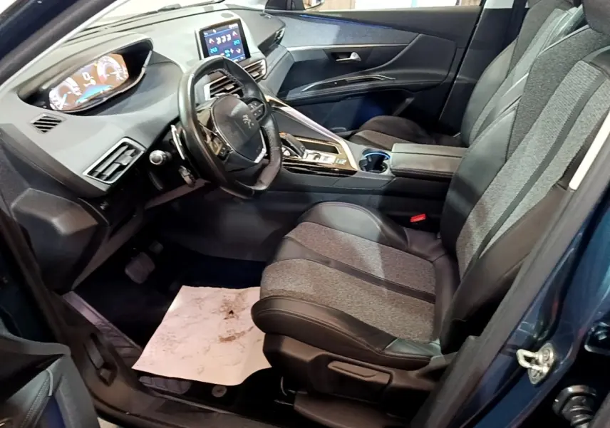Vue intérieure côté conducteur du Peugeot 5008 bleu 2018, avec tableau de bord digital et sièges en tissu et cuir noir.