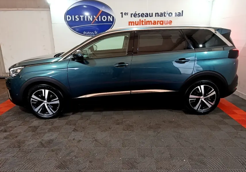 Profil droit du Peugeot 5008 bleu 2018, SUV avec jantes alliage et toit noir contrasté dans un showroom.